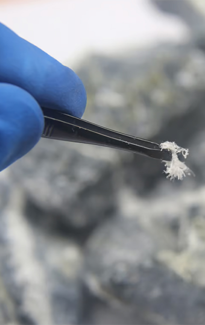 Detailfoto van een handschoen en pincet bij een materiaalstaal, uit de bestaande Asbestix-website
